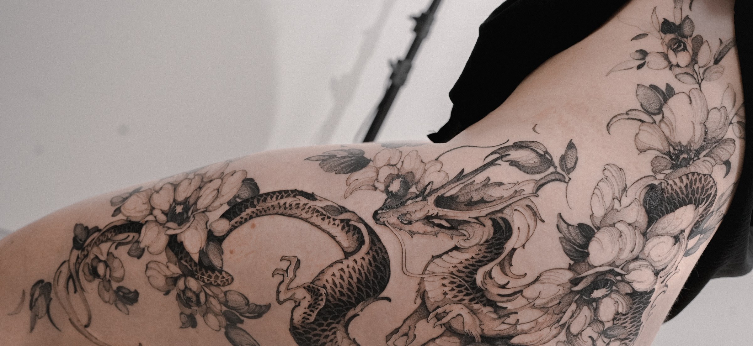 Dragon and peony flowers tattoo flowing along the thigh